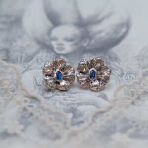 Silver earrings with kyanite in the form of flowers on the background of an illustration